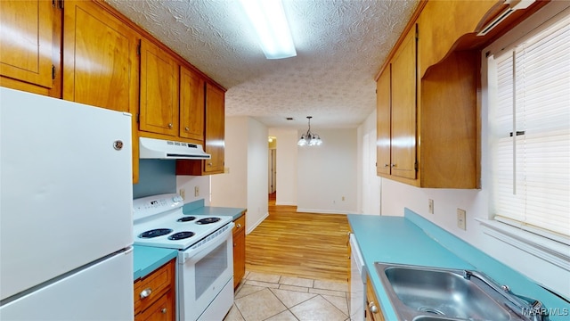 kitchen featuring light hardwood / wood-style flooring, sink, decorative light fixtures, a textured ceiling, and white appliances