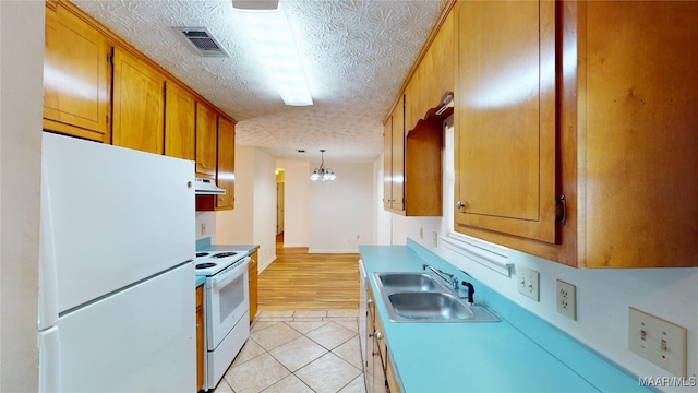 kitchen featuring white appliances, sink, a textured ceiling, decorative light fixtures, and light tile patterned floors