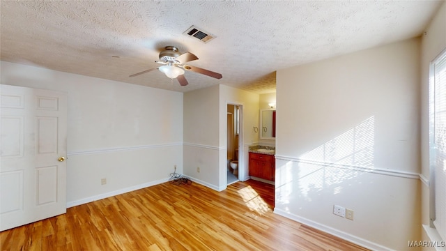 spare room featuring light hardwood / wood-style floors, a textured ceiling, and ceiling fan