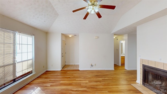 unfurnished living room featuring vaulted ceiling, a textured ceiling, and light wood-type flooring