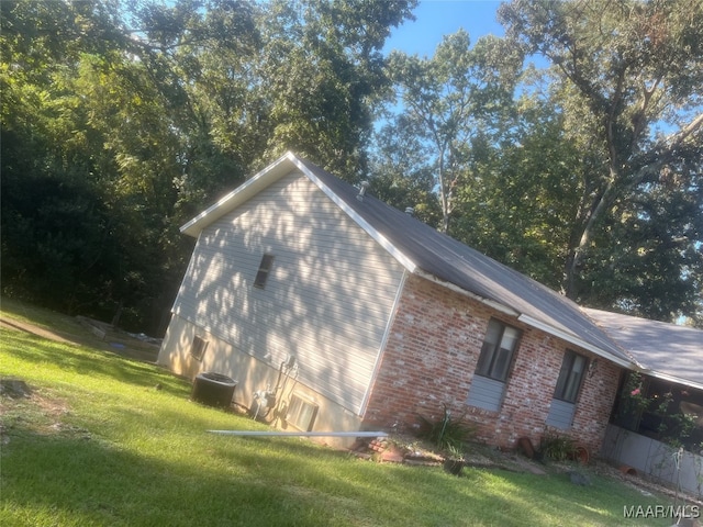 view of side of property with central air condition unit and a lawn