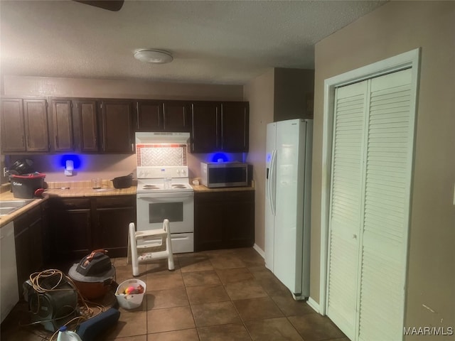 kitchen featuring a textured ceiling, white appliances, and dark tile patterned flooring