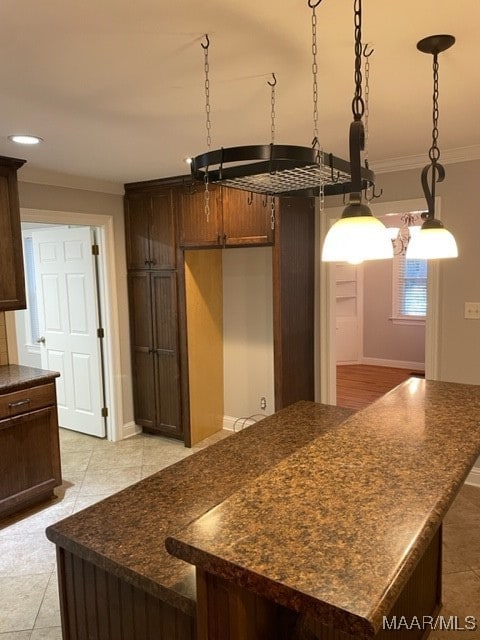 kitchen with light tile patterned floors, decorative light fixtures, ornamental molding, and a kitchen island