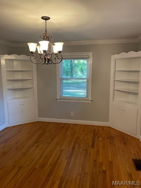 unfurnished dining area with an inviting chandelier, ornamental molding, and hardwood / wood-style flooring