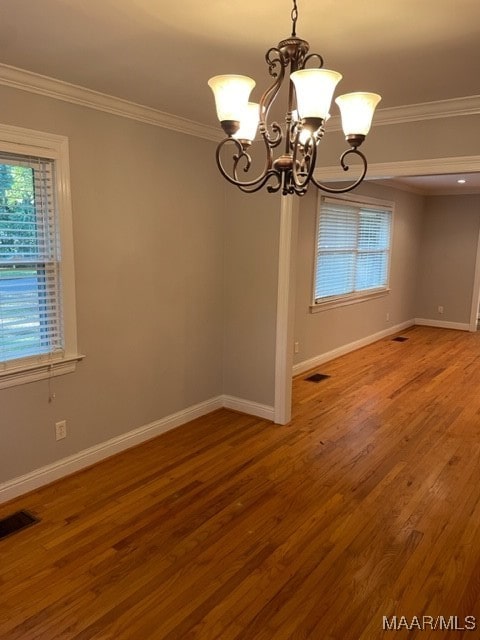 unfurnished dining area featuring a notable chandelier, crown molding, and hardwood / wood-style floors