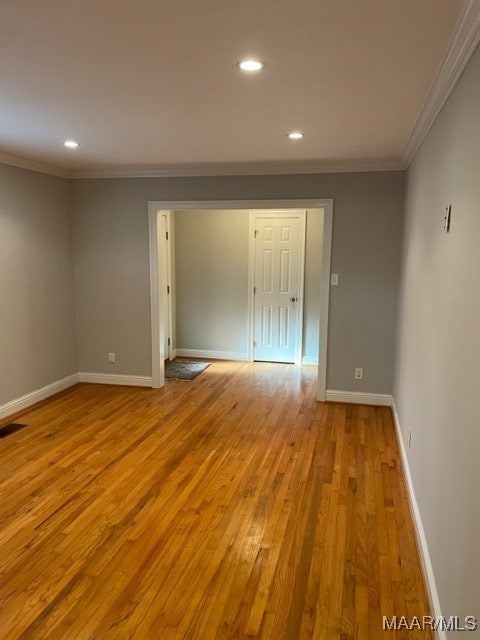 spare room featuring ornamental molding and light hardwood / wood-style flooring