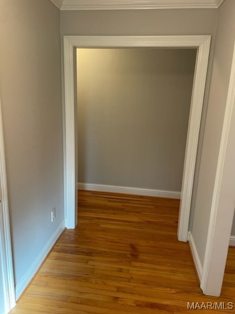 corridor with ornamental molding and light hardwood / wood-style flooring