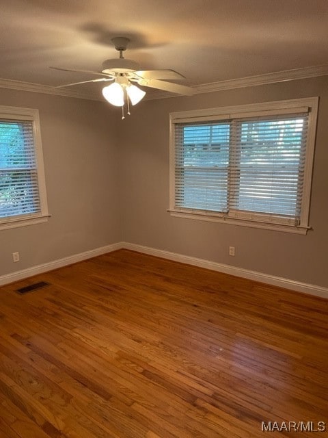 empty room featuring hardwood / wood-style flooring, a healthy amount of sunlight, and crown molding