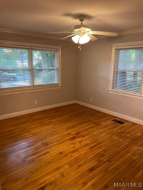 spare room featuring ornamental molding, hardwood / wood-style floors, a wealth of natural light, and ceiling fan