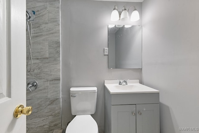 bathroom featuring vanity, a tile shower, and toilet