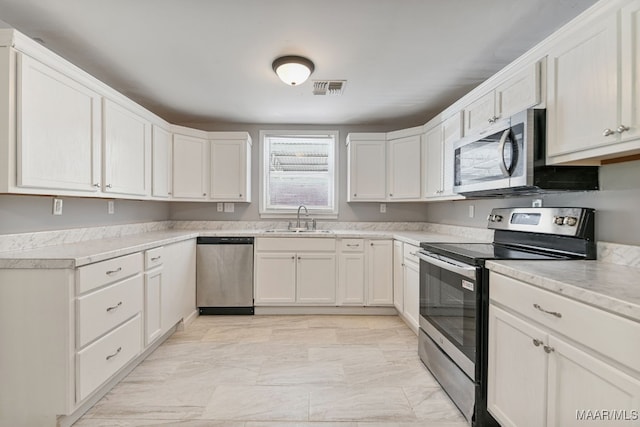 kitchen with stainless steel appliances, sink, and white cabinetry