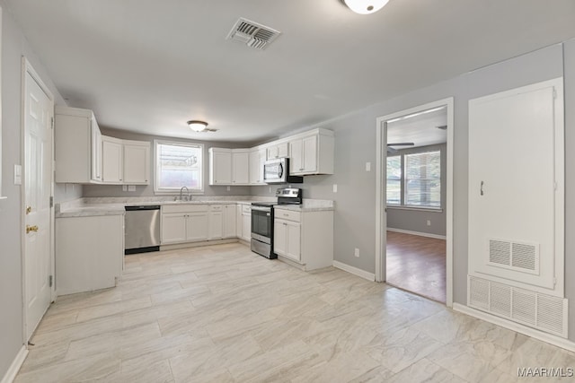 kitchen with white cabinets, appliances with stainless steel finishes, and a healthy amount of sunlight