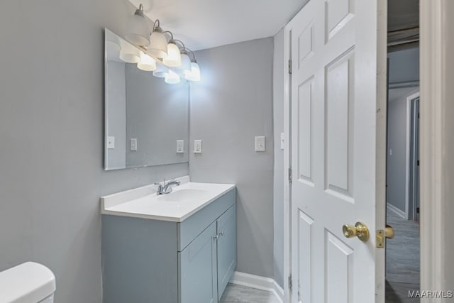 bathroom with an inviting chandelier, vanity, and toilet