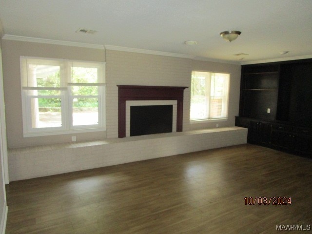 unfurnished living room with crown molding, a brick fireplace, and hardwood / wood-style floors