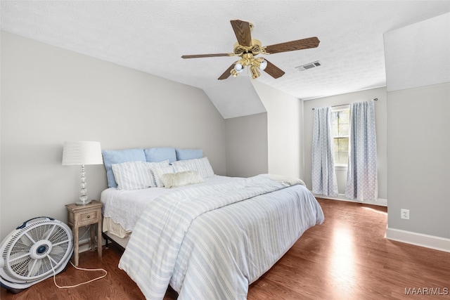 bedroom featuring ceiling fan, vaulted ceiling, a textured ceiling, and dark wood-type flooring