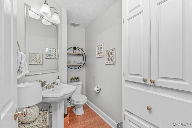 bathroom featuring hardwood / wood-style floors, a textured ceiling, and toilet