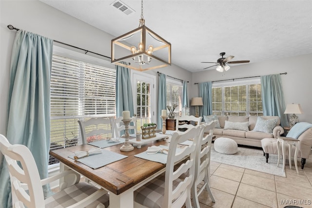 dining room with light tile patterned flooring, ceiling fan with notable chandelier, and a textured ceiling