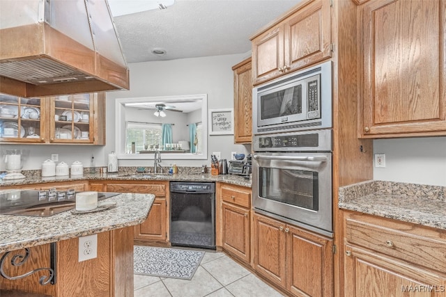 kitchen featuring light stone counters, black appliances, sink, and custom range hood