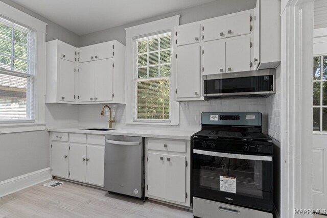 kitchen with white cabinets, appliances with stainless steel finishes, sink, and a healthy amount of sunlight