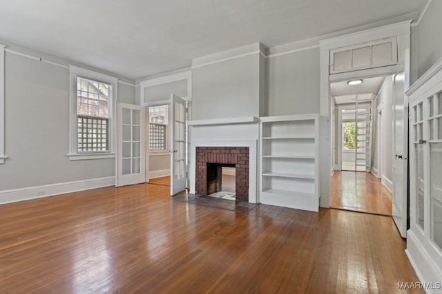 unfurnished living room with a brick fireplace, ornamental molding, and hardwood / wood-style floors