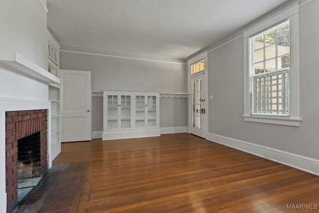 unfurnished living room featuring a brick fireplace and dark wood-type flooring