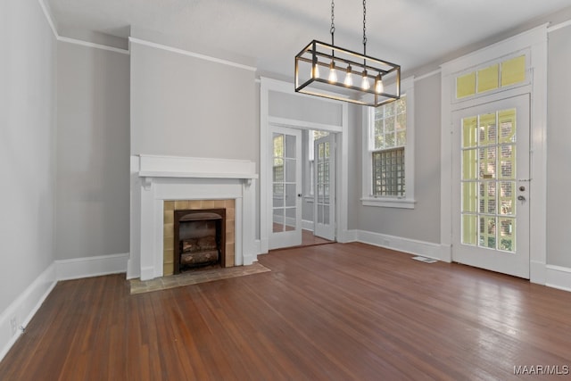 unfurnished living room with a fireplace, crown molding, dark wood-type flooring, and a chandelier