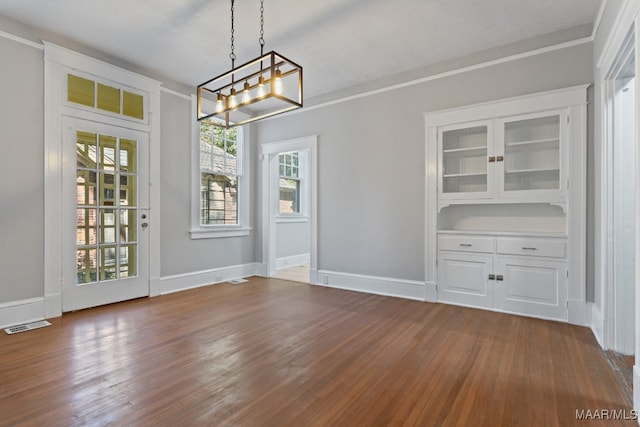 unfurnished dining area with ornamental molding, dark wood-type flooring, an inviting chandelier, and a textured ceiling