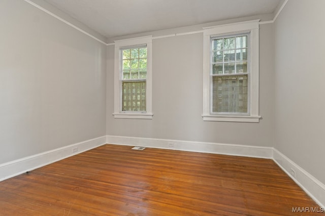 empty room with ornamental molding and hardwood / wood-style floors