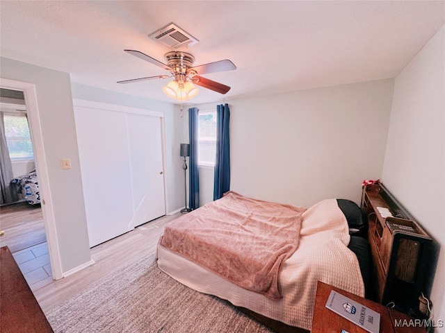 bedroom featuring multiple windows, ceiling fan, a closet, and light hardwood / wood-style floors