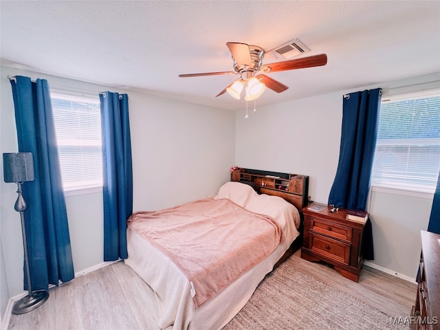 bedroom with a textured ceiling, light wood-type flooring, and ceiling fan