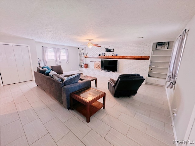 living room with ceiling fan, brick wall, and a textured ceiling