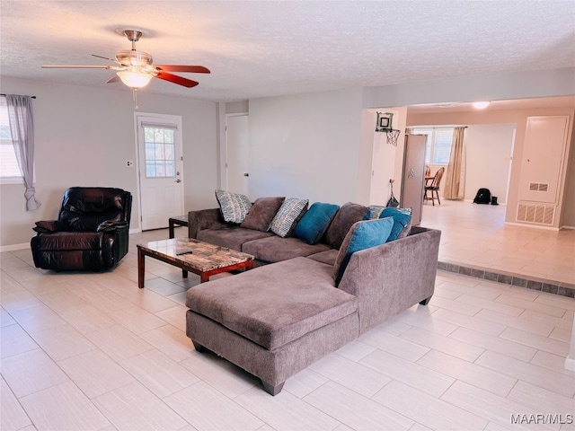 living room with ceiling fan and a textured ceiling