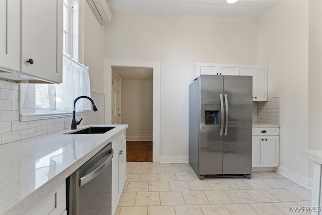 kitchen with a wall unit AC, sink, light stone counters, stainless steel appliances, and white cabinetry