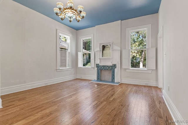 unfurnished living room featuring a premium fireplace, a notable chandelier, and hardwood / wood-style floors