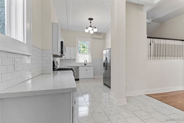 kitchen with light hardwood / wood-style floors, decorative light fixtures, sink, white cabinets, and appliances with stainless steel finishes