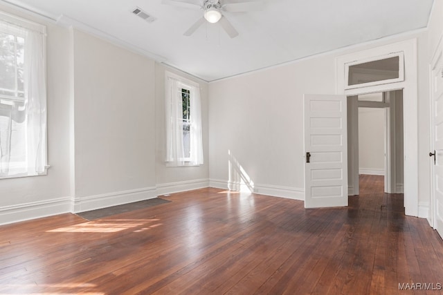 empty room with dark wood-type flooring, crown molding, a wealth of natural light, and ceiling fan