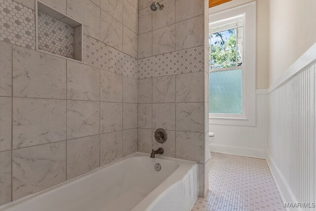 bathroom featuring tile patterned flooring, tiled shower / bath, and toilet