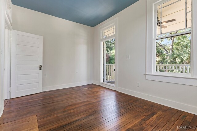 spare room with ceiling fan, a wealth of natural light, and dark hardwood / wood-style floors