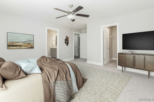 bedroom with ceiling fan, a closet, light carpet, a walk in closet, and ensuite bathroom