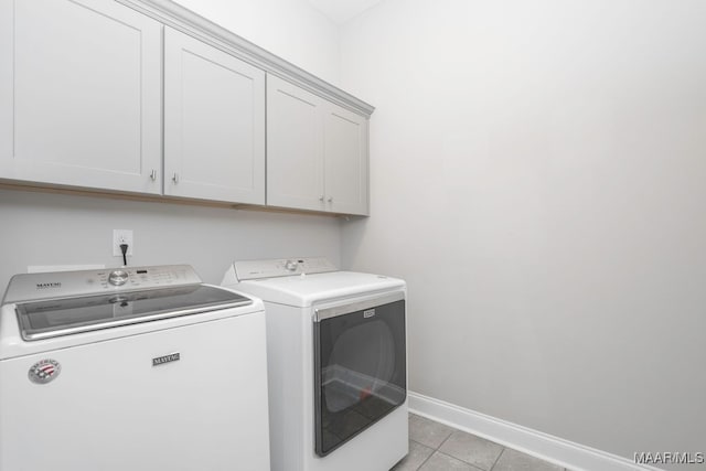 laundry room featuring light tile patterned flooring, washer and dryer, and cabinets