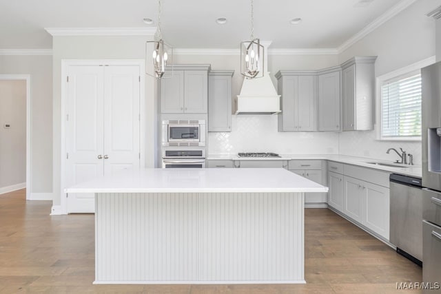 kitchen featuring appliances with stainless steel finishes, a kitchen island, decorative light fixtures, and light hardwood / wood-style floors