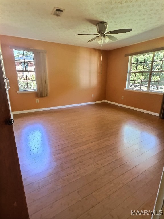 unfurnished room with ceiling fan, hardwood / wood-style flooring, and plenty of natural light