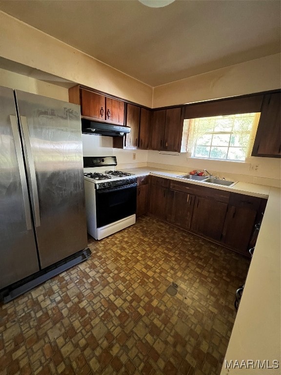 kitchen featuring sink, dark brown cabinetry, stainless steel refrigerator, and white range with gas stovetop