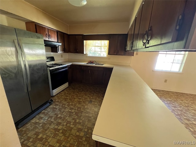 kitchen featuring white gas range, dark brown cabinets, stainless steel refrigerator, and sink