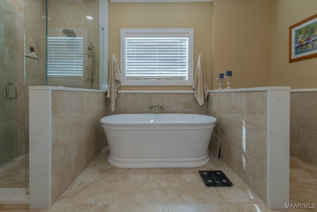 bathroom featuring shower with separate bathtub and tile walls