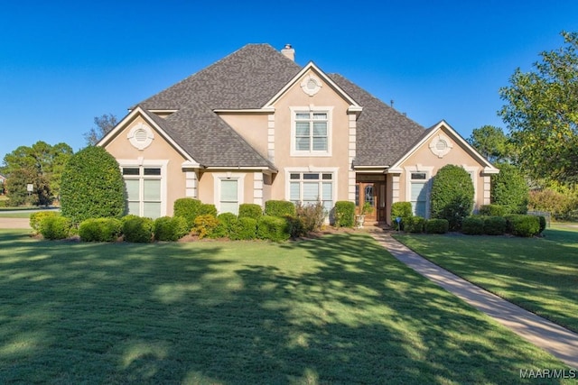 8301 Wynlakes Blvd, Montgomery, AL 36117 - traditional-style house with a front yard, roof with shingles, stucco siding, and a chimney