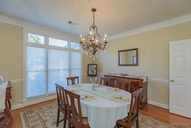 dining space featuring crown molding, an inviting chandelier, and light wood-type flooring