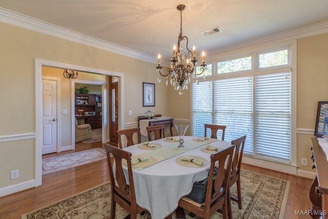 dining area featuring light wood-type flooring, a chandelier, and ornamental molding