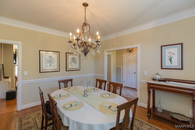 dining area with crown molding, a notable chandelier, and light wood-type flooring