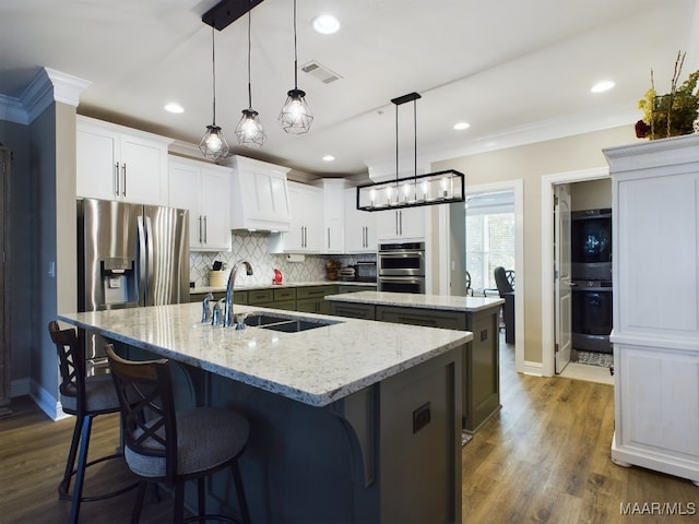 kitchen featuring dark wood-type flooring, a center island with sink, sink, pendant lighting, and white cabinets